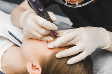 A cosmetologist applies permanent makeup to the eyebrows - eyebrow tattoo. eyebrow perm