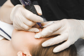 A cosmetologist applies permanent makeup to the eyebrows - eyebrow tattoo. eyebrow perm