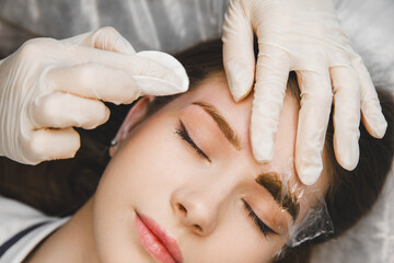 A cosmetologist applies permanent makeup to the eyebrows - eyebrow tattoo. eyebrow perm