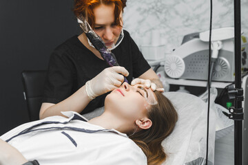 A cosmetologist applies permanent makeup to the eyebrows - eyebrow tattoo. eyebrow perm