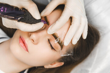 A cosmetologist applies permanent makeup to the eyebrows - eyebrow tattoo. eyebrow perm