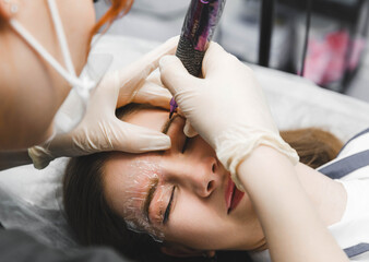 A cosmetologist applies permanent makeup to the eyebrows - eyebrow tattoo. eyebrow perm