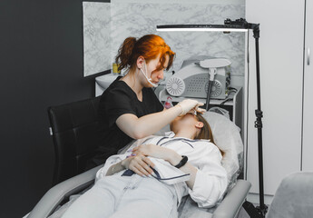 A cosmetologist applies permanent makeup to the eyebrows - eyebrow tattoo. eyebrow perm