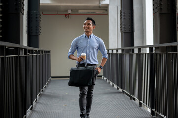 A handsome and confident Asian millennial businessman walking along the building corridor.