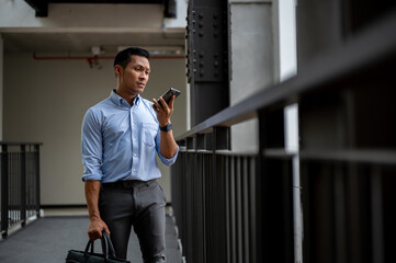 A confused, uncertain Asian millennial businessman checking messages on his smartphone.