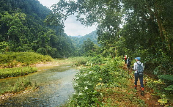 Group of hikers in jungle walk along path along river to famous Phong Nha Caves in Vietnam.