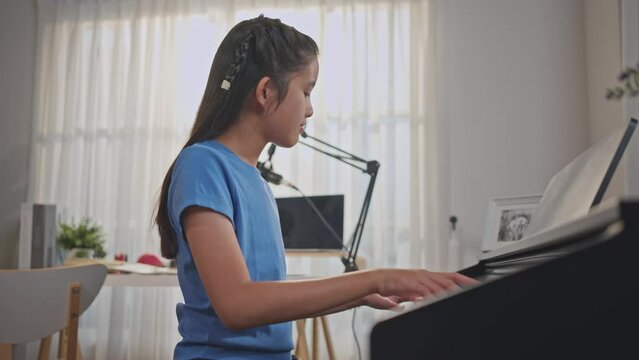 Asian adorable child artist playing electronic piano in music record studio. 