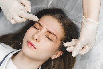 A cosmetologist applies permanent makeup to the eyebrows - eyebrow tattoo. eyebrow perm