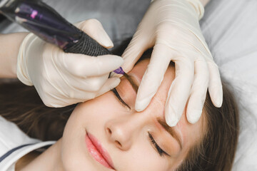 A cosmetologist applies permanent makeup to the eyebrows - eyebrow tattoo. eyebrow perm