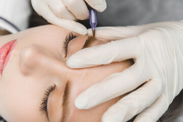 A cosmetologist applies permanent makeup to the eyebrows - eyebrow tattoo. eyebrow perm