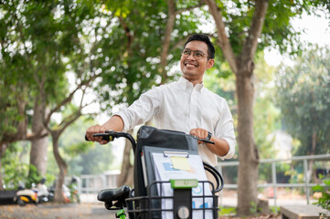A happy, carefree Asian businessman pushing his bike, walking in the public park.