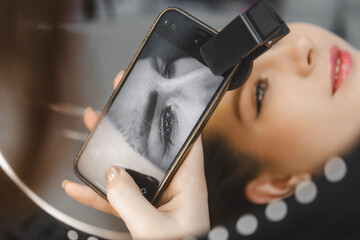 A tattoo artist takes a photo of his client on his phone after permanent eyebrows.
