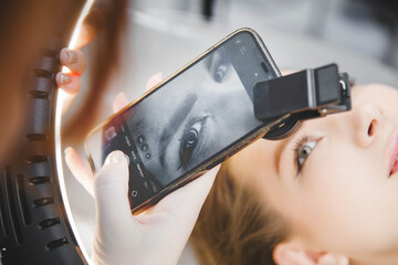 A tattoo artist takes a photo of his client on his phone after permanent eyebrows.