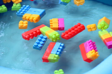 building blocks are floating in the water and giving resemblance of tsunami. during Tsunami how the buildings and vehicles float in the water. this is what child play during the summer