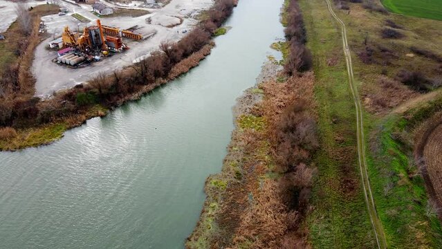 Drone flies over buildings and machinery of industrial zone on riverbank of Bega