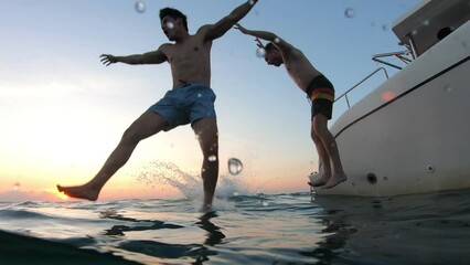 Group of young friends jumping to the beach, having a party in yacht.  - Powered by Adobe