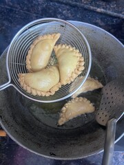 Gujiya or gujia or karanji, sweet dumplings being deep fried in cooking pan during the festival occasion of Holi and Diwali
