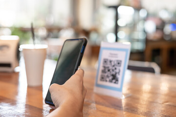 man use smartphone to scan QR code to pay in cafe restaurant with a digital payment without cash....