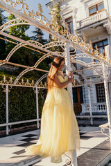 beautiful woman in a long puffy yellow dress posing near the arch