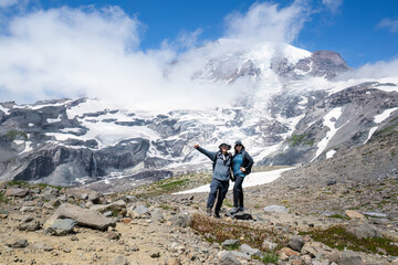 Couple posing for photos at Skyline Trail with Mt Rainier in the background. Mt Rainier National Park. Washington State.