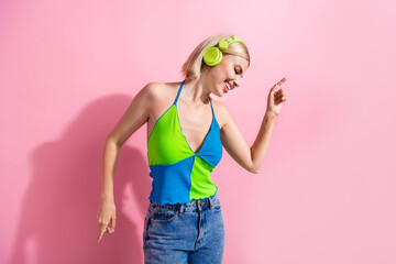 Portrait of positive lovely woman with bob hair wear colorful top listen playlist in headphones dancing isolated on pink color background