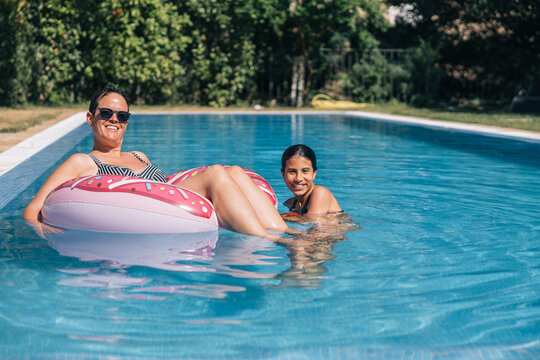 Mother and daughter in the pool playing with an inflatable doughnut