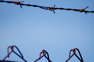 metal barbed wire on a background of clear blue sky, close-up. detail of barbed wire fence
