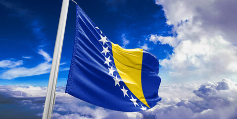 Bosnia and Herzegovina national flag cloth fabric waving on beautiful Blue Sky Background.