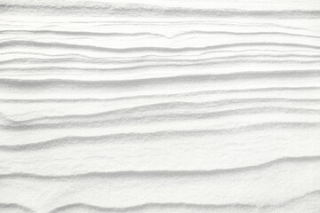 Surface of the earth covered with white snow, with an abstract pattern in the form of waves formed...