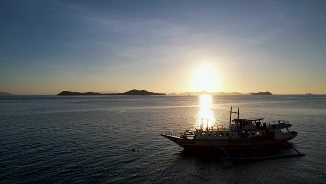 Traditional philippine boat bangka at sunset time in Linapacan, Philippines. Orange sky sunset paradise beach.