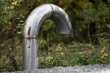 Large industrial curved silver pipe in a park