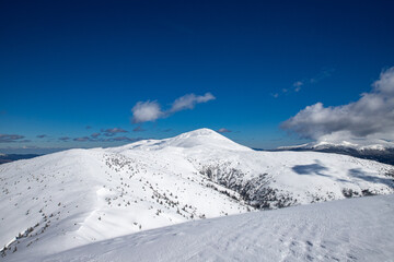 above the clouds, hiking in the winter mountains, snowy mountain peaks and blue sky