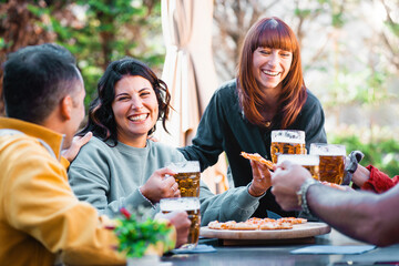 Close-knit friends share a hearty laugh over chilled beer and pizza in an outdoor garden - a moment...