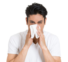 Closeup portrait of sick young man with allergy or germs cold, blowing his nose looking miserable unwell very sick, isolated on white background. - 781951434