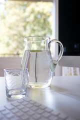 Vertical shot of water carafe with glass on table