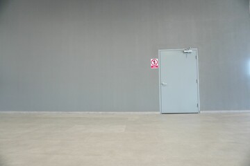 Landscape shot of a grey metal door attached on a grey wall