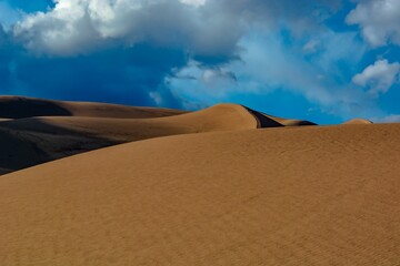 Scenic view of a desert under a bright blue and cloudy sky