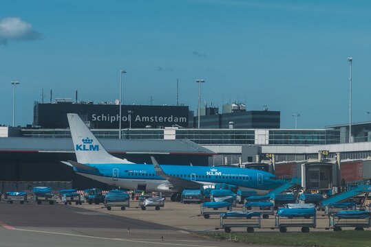 KLM airplanes at the terminal waiting for passengers. Aircraft control tower in the background.