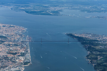 Aerial view of April 25th bridge, an iconic landmark suspended bridge crossing Tagus river with Lisbon city downtown in the background, Portugal.