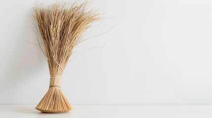 a straw broom against a white backdrop