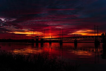 Scenic view of beautiful scarlet sunset sky with abstract clouds over bridge