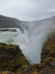 Vertical shot of the Gullfoss waterfall in Hvita, Iceland covered in steam under a cloudy sky