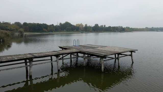 Drone flies over wooden pier with stairs on a large lake Zobnatica in Serbia