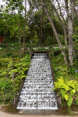 Waterfall cascades in Monte Palace Tropical Garden in Madeira, Portugal, surrounded by green trees