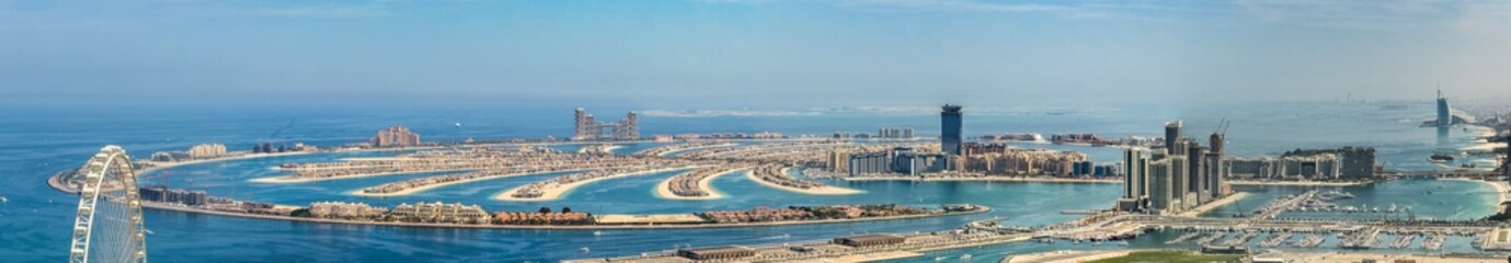 panoramic aerial city view of Dubai with the artificial island Palm Jumeirah and many other famous buildings along the coastline of Dubai