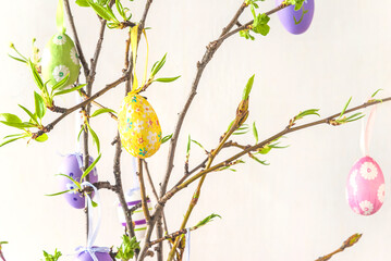 Easter holiday concept; Twigs decorated by easter eggs on a white background; selective focus