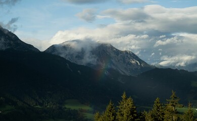 Aerial shot of a mountain peak under the clouds and evergreen trees