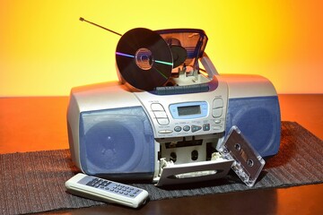 CD music player and cassettes on table with orange light in background.