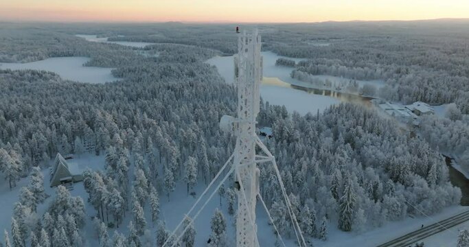 Radiotower in middle of snow covered arctic wilderness, sunset in Lapland - Aerial view