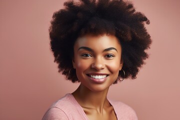 A woman with curly hair is smiling and wearing a pink shirt
